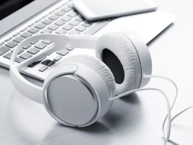 białe słuchawki komputerowe obok klawiatury